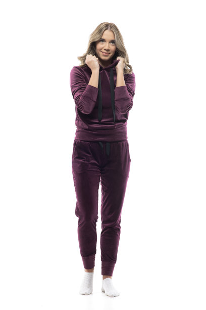 可爱女性的年轻女子在酒红色连帽运动衫和长毛绒运动裤微笑。图片下载