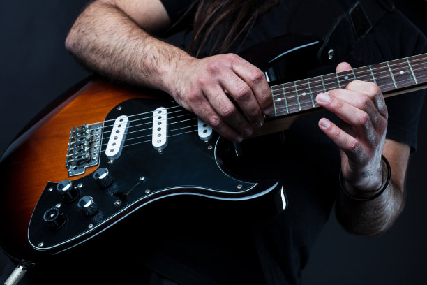特写吉他手的演奏，以黑色背景。图片下载
