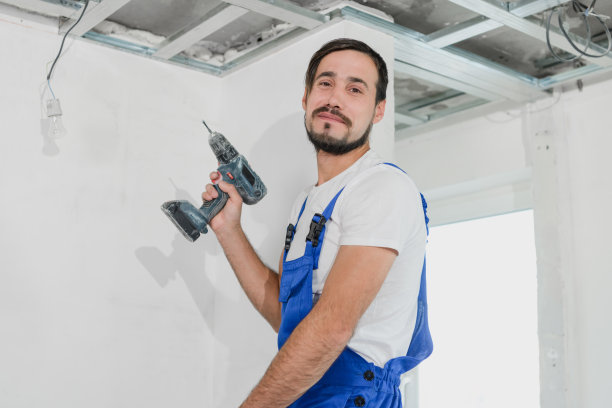 建筑工用钻机和工作服看着摄像机图片下载