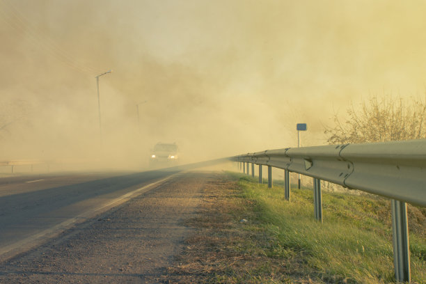 一辆汽车在郊区高速公路上行驶时，路边起火，浓烟滚滚图片下载