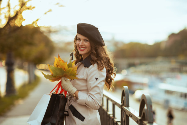 微笑的女性与购物袋和秋天的树叶图片下载