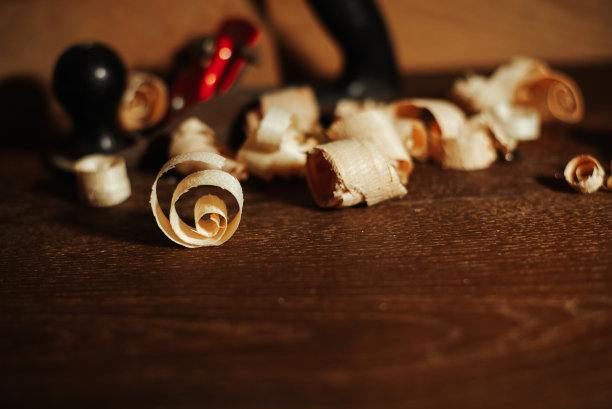 木匠工作的桌子上有工具和工艺品，木桌上有木屑和工具。图片下载