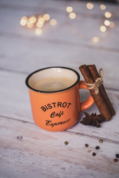 白色木质背景上放着圣诞香料的橙色咖啡杯图片下载