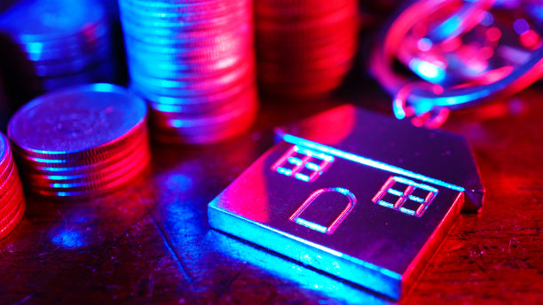 渐变的浅蓝色和红色的光线装饰房子的钥匙扣与硬币堆叠在桌子上，银行技术概念，重点在钥匙扣。图片下载