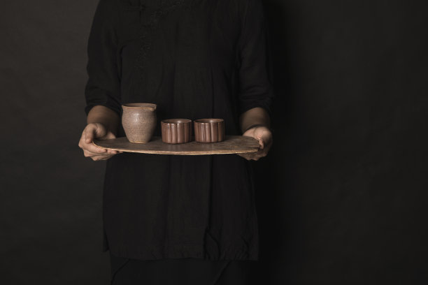 一位女士的手端着一盘茶杯。图片下载