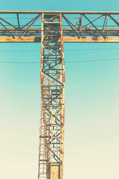 旧的，生锈的门式起重机在铁路上，一个废弃的混凝土工厂。危机、经济崩溃和生产能力的关闭导致了崩溃。全球灾难。一张古老照片的效果。图片下载