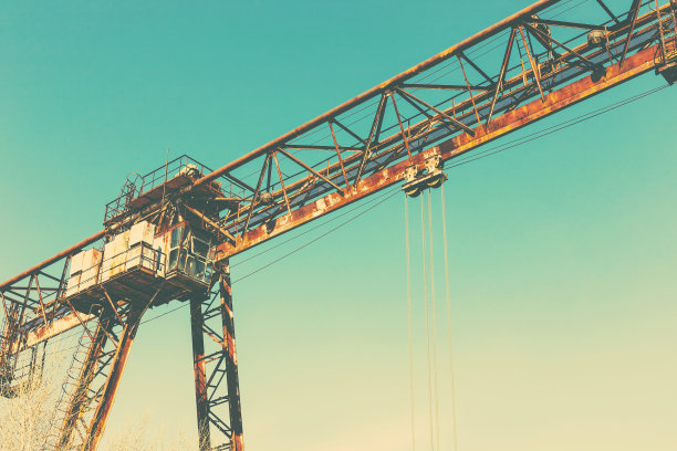 旧的，生锈的门式起重机在铁路上，一个废弃的混凝土工厂。危机、经济崩溃和生产能力的关闭导致了崩溃。全球灾难。一张古老照片的效果。图片下载