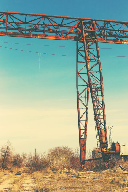 旧的，生锈的门式起重机在铁路上，一个废弃的混凝土工厂。危机、经济崩溃和生产能力的关闭导致了崩溃。全球灾难。一张古老照片的效果。图片下载