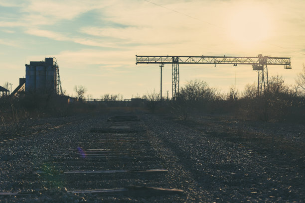 旧的，生锈的门式起重机在铁路上，一个废弃的混凝土工厂。危机、经济崩溃和生产能力的关闭导致了崩溃。全球灾难。一张古老照片的效果。图片下载