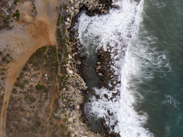 空中自上而下的照片，泡沫海浪撞击岩石海岸，海岸线上的大石头。爱琴海，希腊克里特岛的大自然。海洋自然图案，背景壁纸。图片下载