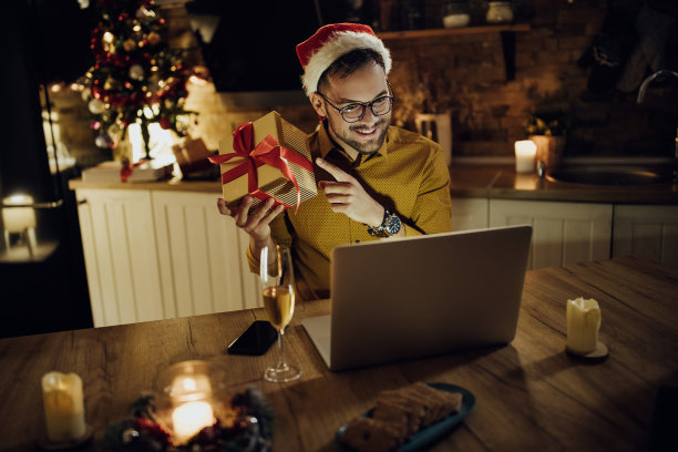 圣诞节晚上用笔记本电脑和某人在线聊天的快乐男人。图片下载