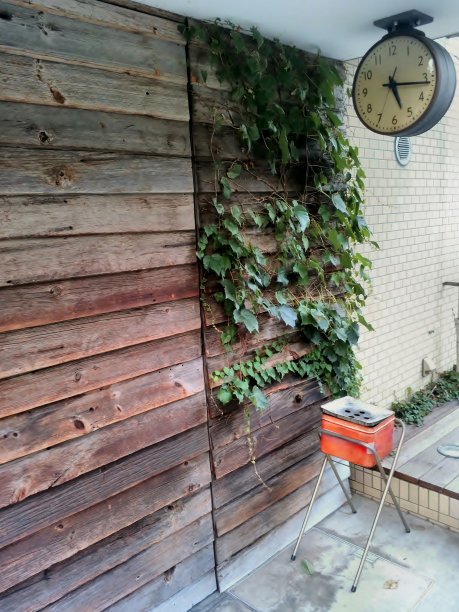 大厦外指定吸烟区红色烟灰缸及挂钟。图片下载