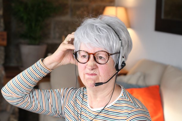 愤怒的高级女性在家里使用耳机图片下载
