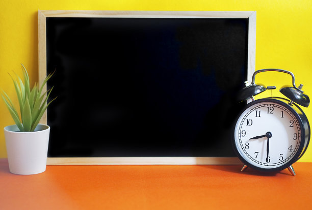 闹钟和黑板在黄橙色的背景。图片下载