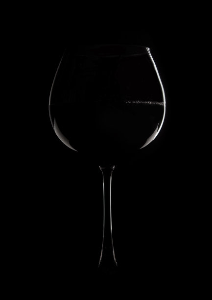 黑色背景上的葡萄酒酒杯照片。玻璃的边缘被光线照亮。图片下载