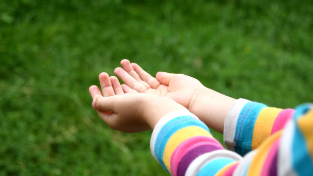 蹒跚学步的孩子的手抓住雨滴进入手掌特写图片下载