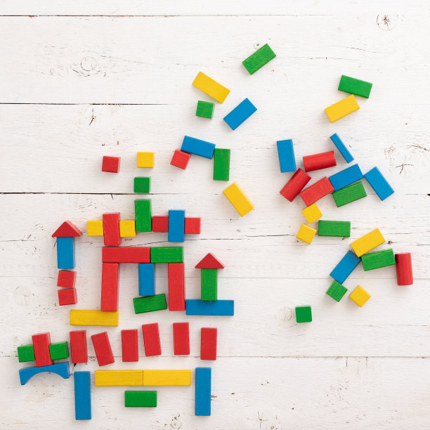 顶视图上的木制彩色砖在一个白色的木制背景。一个孩子用散落在桌子周围的五颜六色的木块建造一座城堡。学校、教育、学习的理念。图片下载