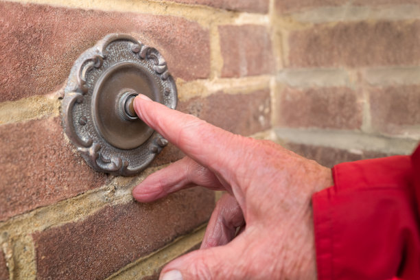 一个复古的古色古香的金属门铃被一只红色袖子的男性的手推着图片下载