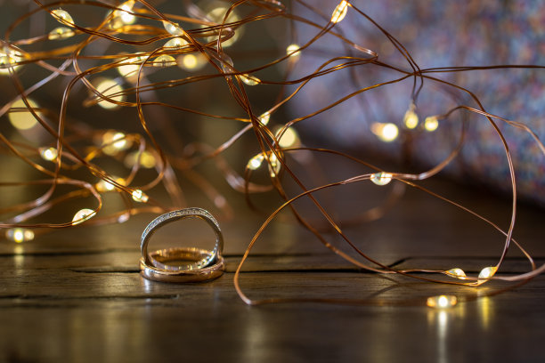 木桌上放着订婚戒指和灯。图片下载