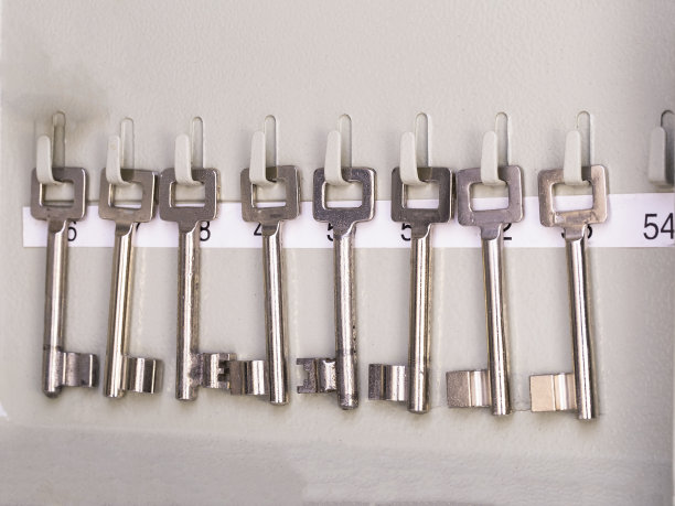 一排古老的金属银万能钥匙挂在标有房间号码的架子上。古董古董钥匙图片下载