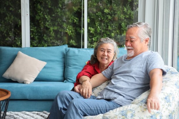 资深亚洲夫妇花时间一起在他们的养老金舒适的家，而坐在沙发上图片下载