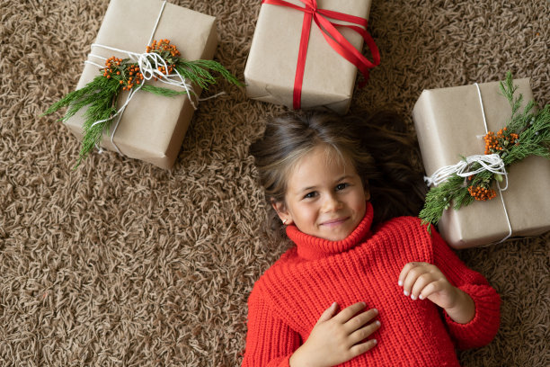 一个具有欧洲人外貌的女孩穿着一件红毛衣。躺在包装好的箱子旁边的地板上。图片下载