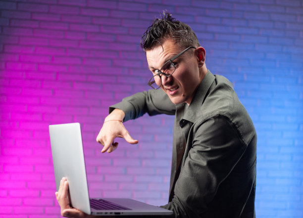 一个戴着眼镜和笔记本电脑的疯子在明亮的霓虹灯背景下图片下载