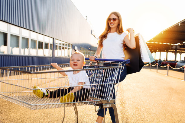 幸福的家庭，兴奋，快乐的妈妈带着孩子推着购物车走在购物中心附近的街道上图片下载