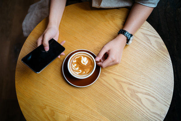 拿着拿铁咖啡，用手机的女人图片下载