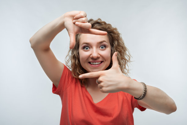 有趣的女人微笑的照片，用手指做相框。人的情绪、表情概念图片下载