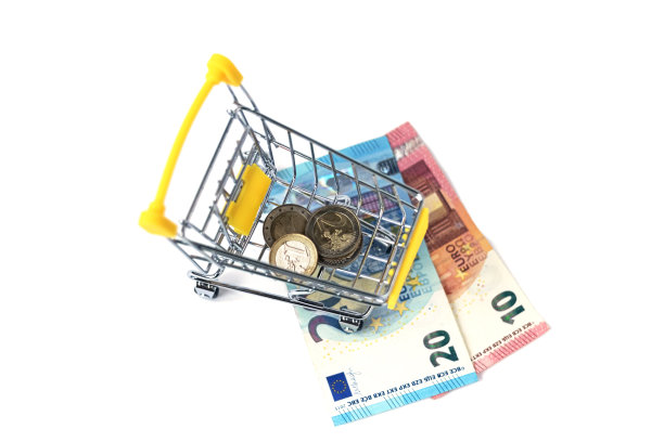 装满欧元现金和硬币的小购物车。黄色购物车四枚硬币，30欧元。消费和购物的概念。图片下载