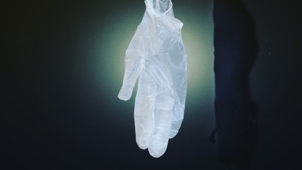 Covid 19。在黑色背景上的一个光点上的医用手套。图片下载