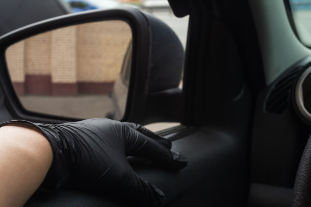 一个男人的手戴着黑色医用手套放在打开的车窗里。防病毒安全概念图片下载