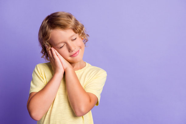 照片上的小男孩睡觉舒适舒适的空空间孤立在紫罗兰色的背景图片下载