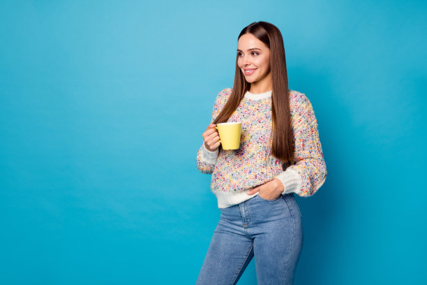 美丽迷人的女士的照片长直发呆在家里隔离喝热咖啡饮料看一边空的空间穿休闲毛衣牛仔裤孤立的蓝色背景图片下载