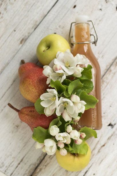 一瓶苹果和梨汁，新鲜的梨，苹果和花在一个白色的木制背景。乡村风格图片下载