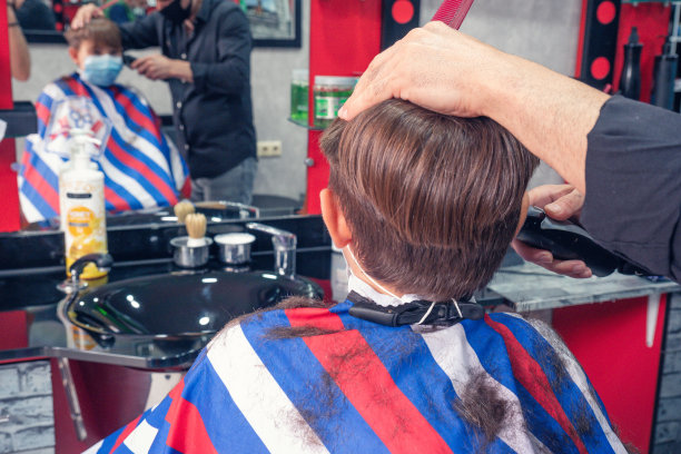 戴着防护面具的男孩在新的正常时期理发。图片下载