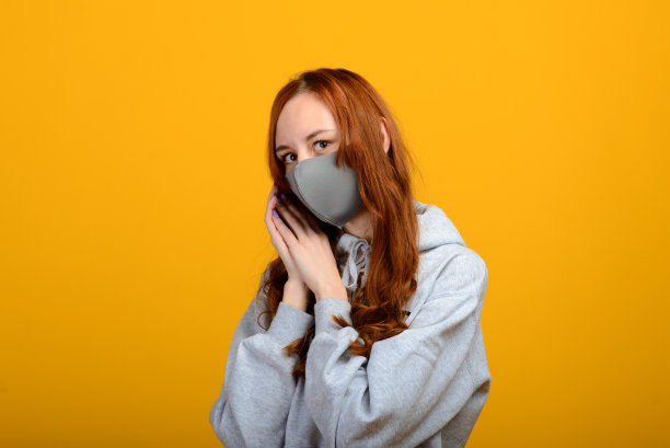 一个戴着面具的女孩的肖像，戴着橡胶手套。黄色背景。图片下载