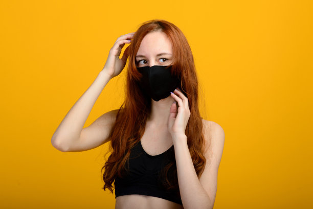 一个戴着面具的女孩的肖像，戴着橡胶手套。黄色背景。图片下载