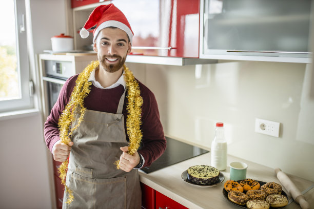 肖像快乐的年轻人穿着围裙和准备圣诞晚餐的食物图片下载