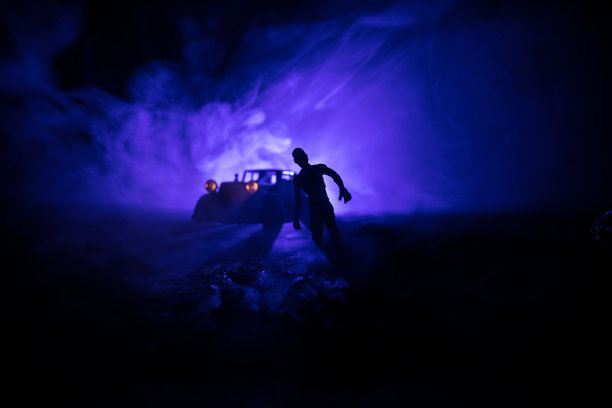 一辆停在路上的车点燃了僵尸的照片。可怕的僵尸剪影夜晚附近的汽车。小型装饰。图片下载