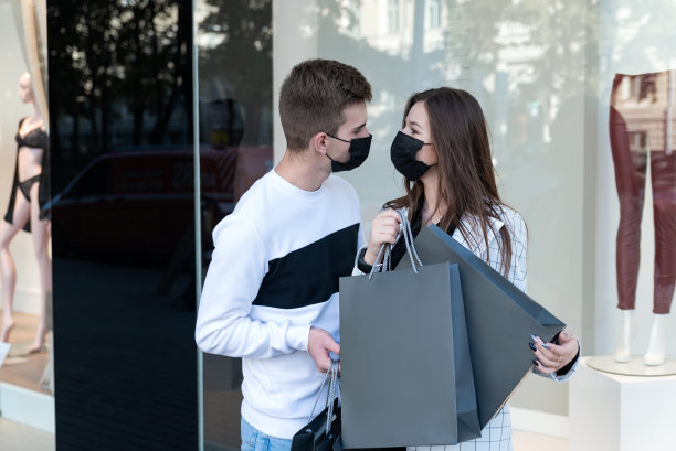 情侣购物后戴着医用口罩，手里拿着包装。黑色星期五和隔离图片下载