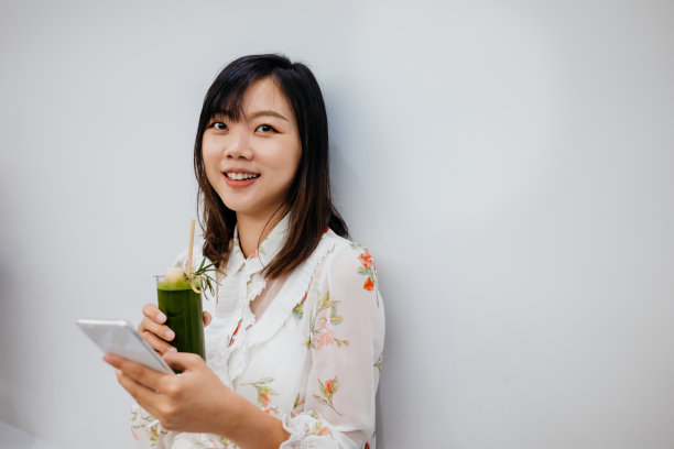 微笑的亚洲女性在咖啡馆使用智能手机素材图片