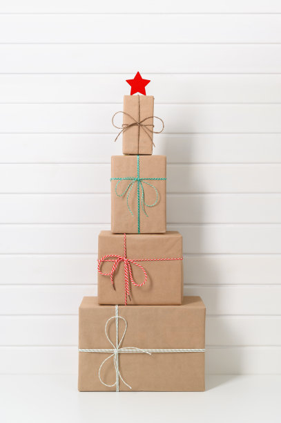 另一种圣诞树由礼物盒与白色的星星在背景的白色木墙。图片下载