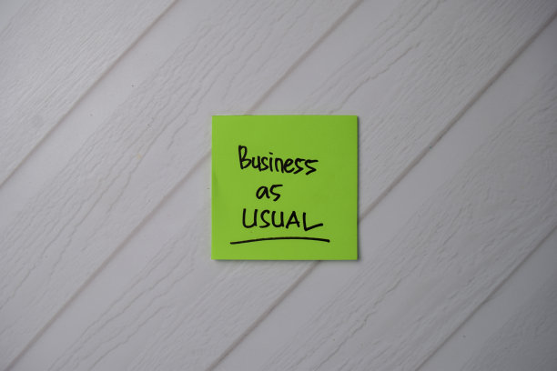 在办公桌边的便利贴上写着“一如既往”。随手贴在办公桌上的便签上。图片下载