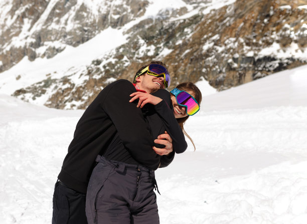 微笑的情侣拥抱，戴着滑雪镜，在美丽的冬季山上。冬季旅游，家庭观念。图片下载