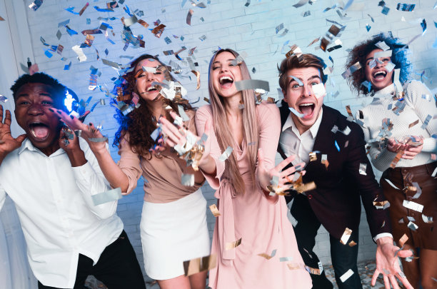 兴奋的年轻人站在室内庆祝闪亮的五彩纸屑图片下载