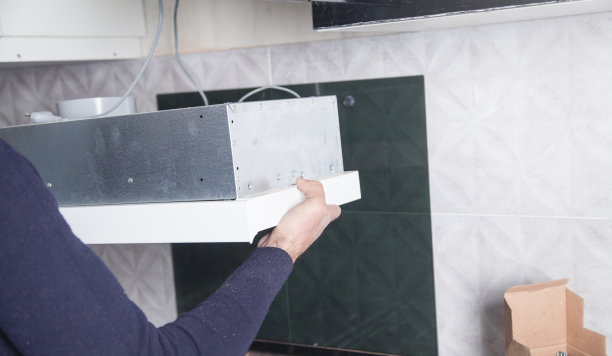 工人在厨房安装排风装置。图片下载
