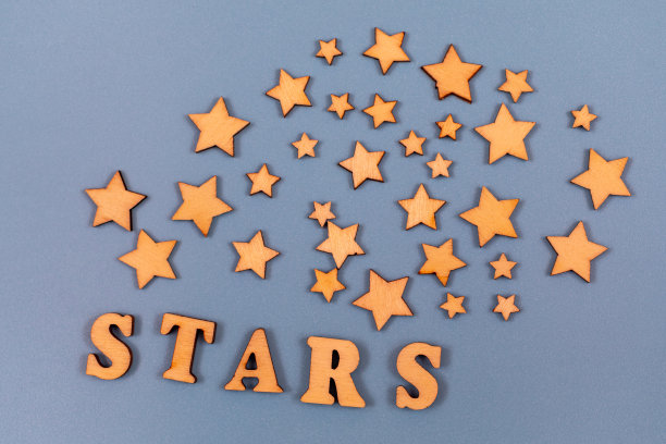 在灰色的背景上用木制字母写的单词星星。用木制星星装饰。设计或概念表上的文字。图片下载