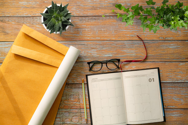 大理石桌上放着一本翻开的笔记本，上面铺着灰色的纸。模型与文本空间。从上面看，桌子上有一副眼镜，仙人掌，木框。全景的照片图片下载